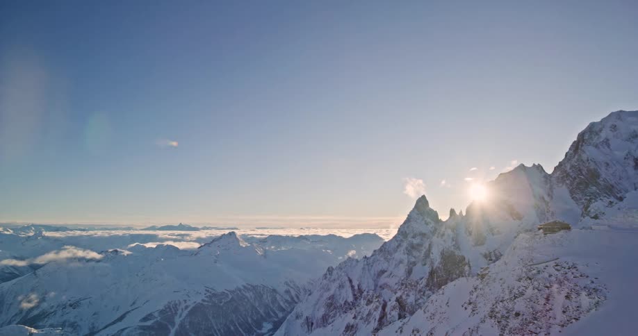 Aerial view of the sun setting behind snow capped mountain range