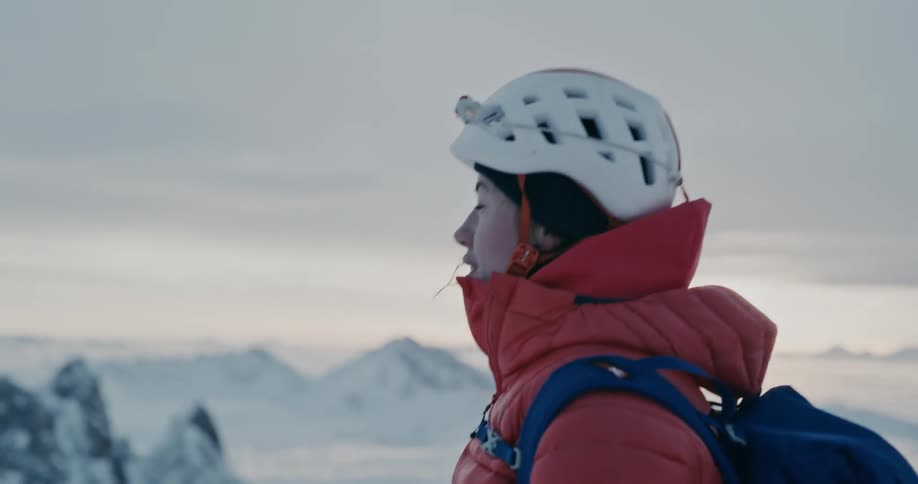 Female backpacker hikes through snowy mountainous terrain in winter