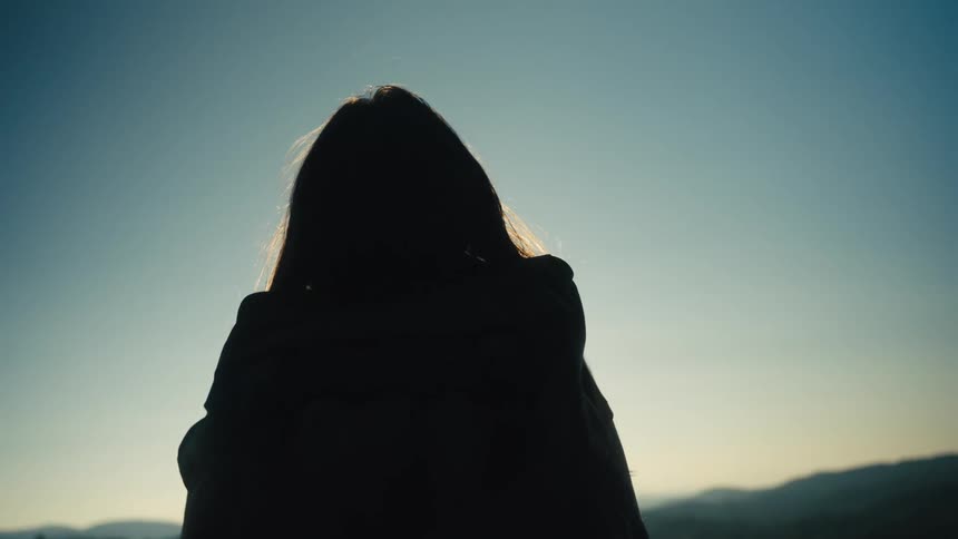 Silhouette of a woman walking out of a forest in the mountains