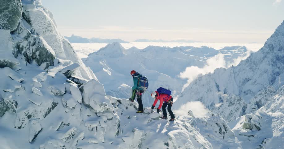 Two mountaineers climbing a snow covered mountain peak