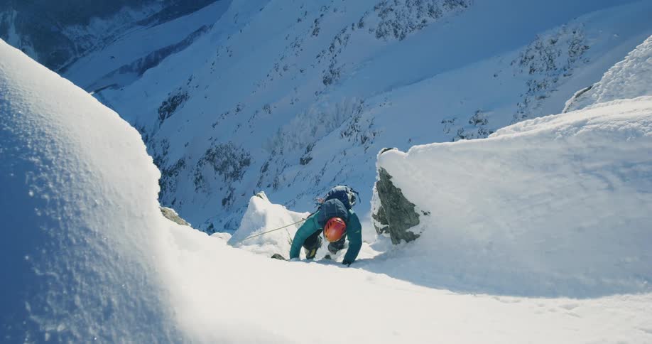 Views of a man climbing amidst a snowcovered mountain