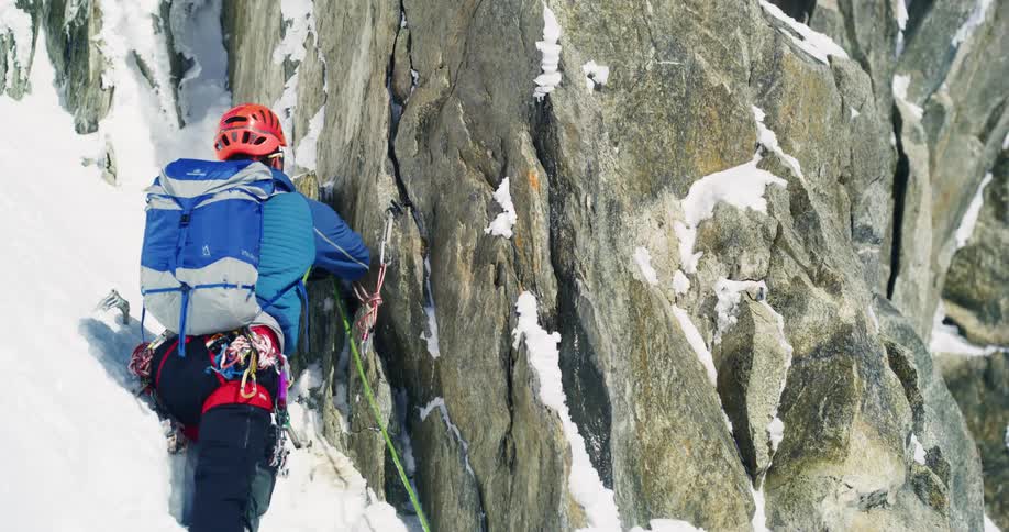 Mountaineer secures a rope on a rock wall in the mountains