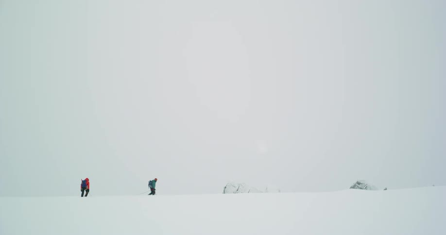 Two people hiking on a trail through snow during the day