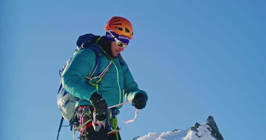 A man tying a rope to a snowcovered rock