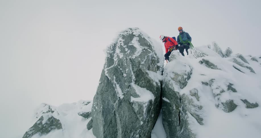 Two people going down on a mountain covered in snow at midday