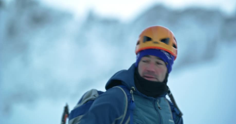A man with a reinforced helmet is pulling a rope that is on the snowy ground