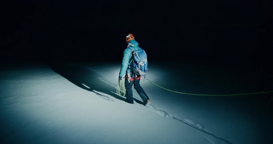 Two people hike in the snow at night