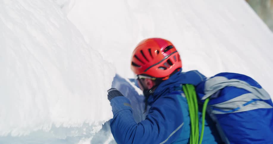 A climber is digging a hole in the snow to climb