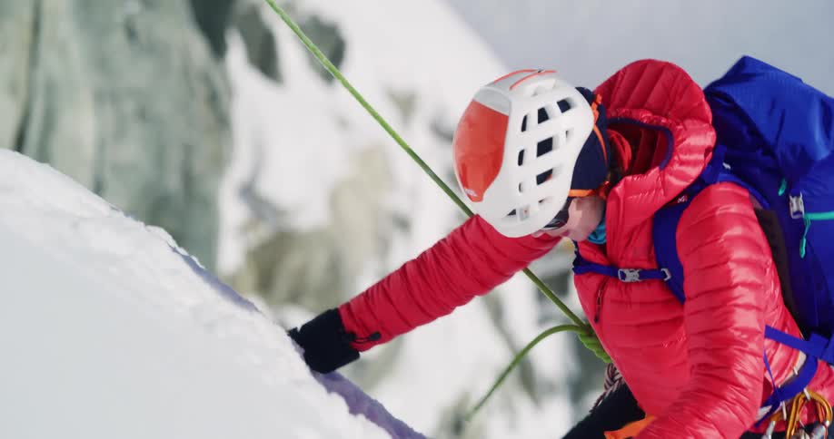 A man climbing a snow mountain using hooks and rope at midday