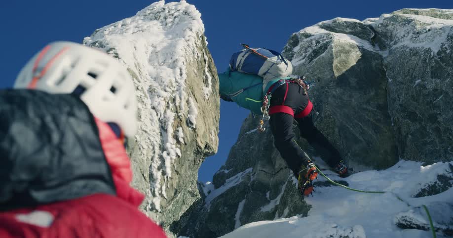 People climb a snowcovered mountain during a cold day