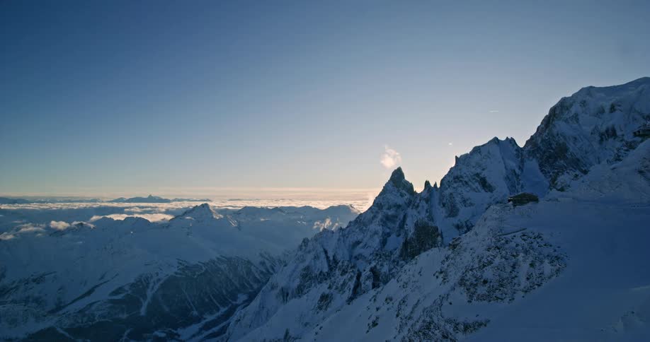 The sun shines over a snow covered mountain peak