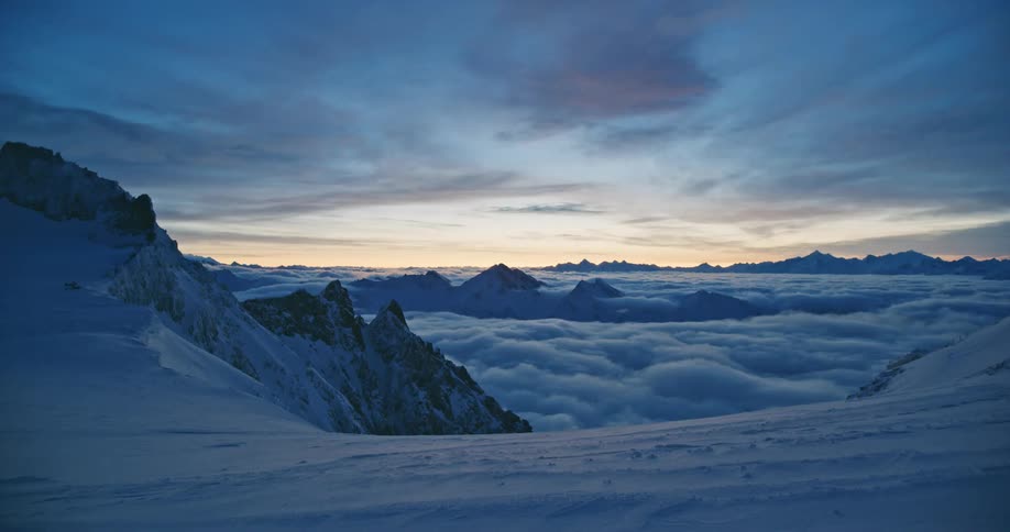 Snow covered mountains high in the clouds with mountains in the distance