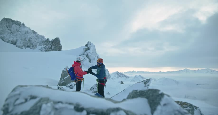 Two mountaineers share a drink atop a mountain