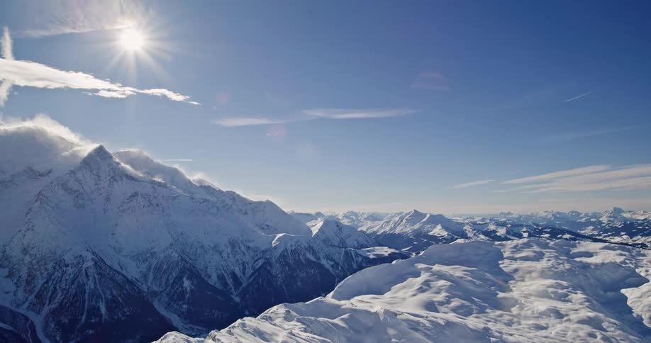 Aerial view of the sun shining over a snowcovered mountain range