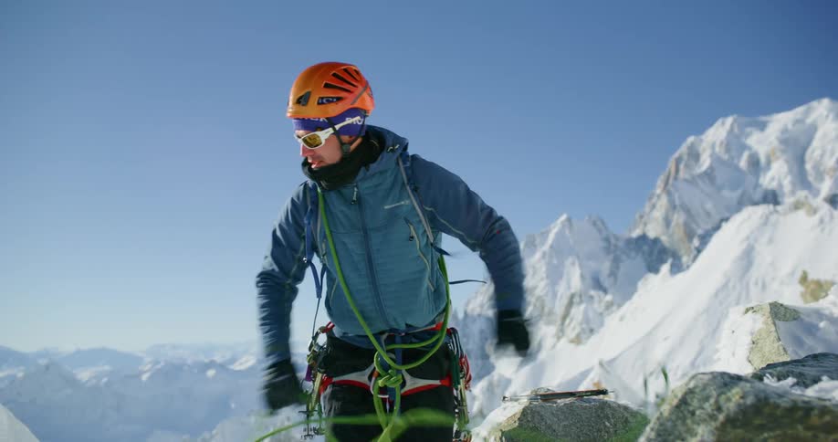 Man pulling a green rope in the midst of a snowcovered mountain in daylight