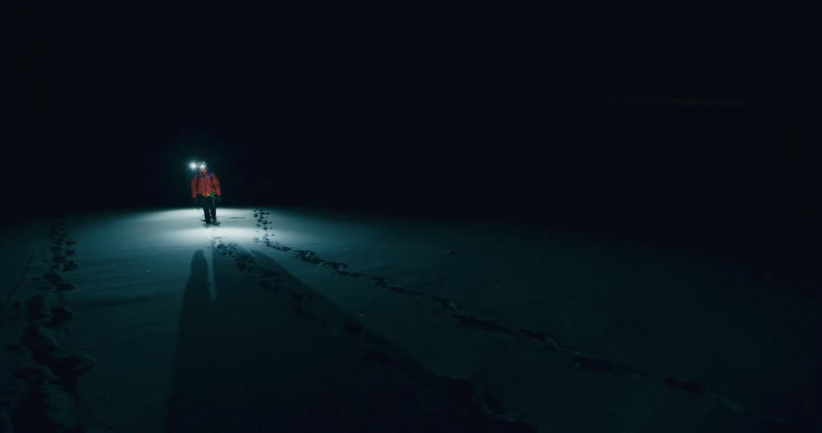 Panorama of two people with lanterns walking in the midst of snowcovered mountains at night
