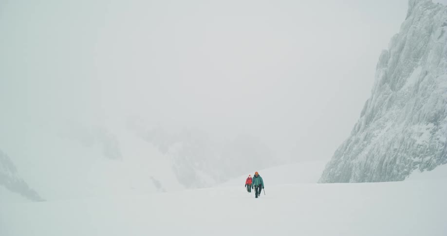 Mountain climbers walking up a snow covered slope on a snow covered hill