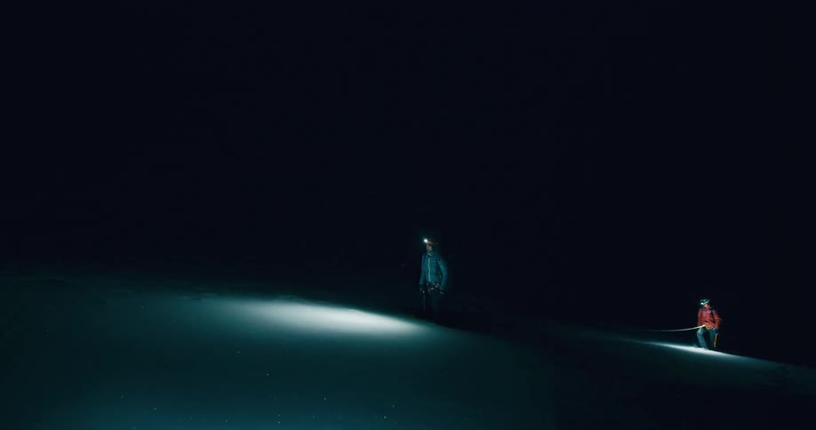 Man and woman walking under a snowcovered mountain at night