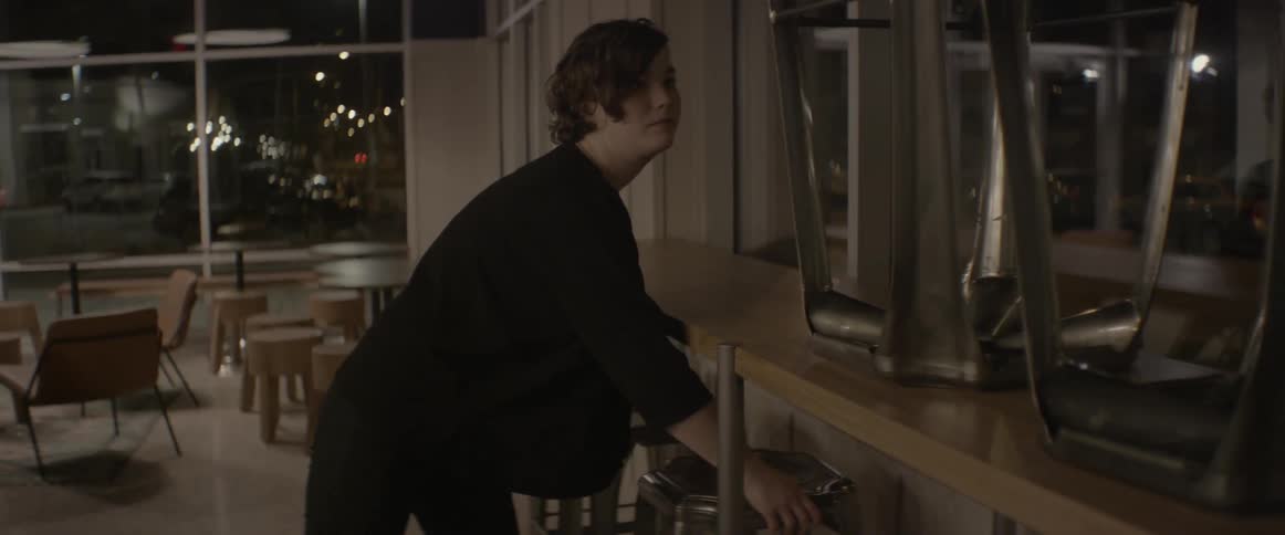 A woman removes the stools from the top of a table by the window