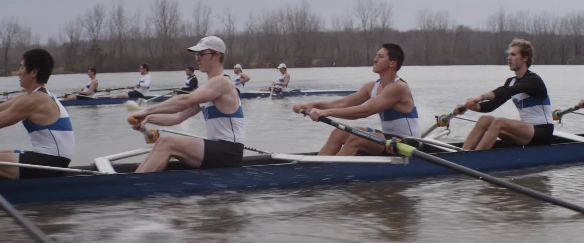 Male rowing teams compete on an overcast day