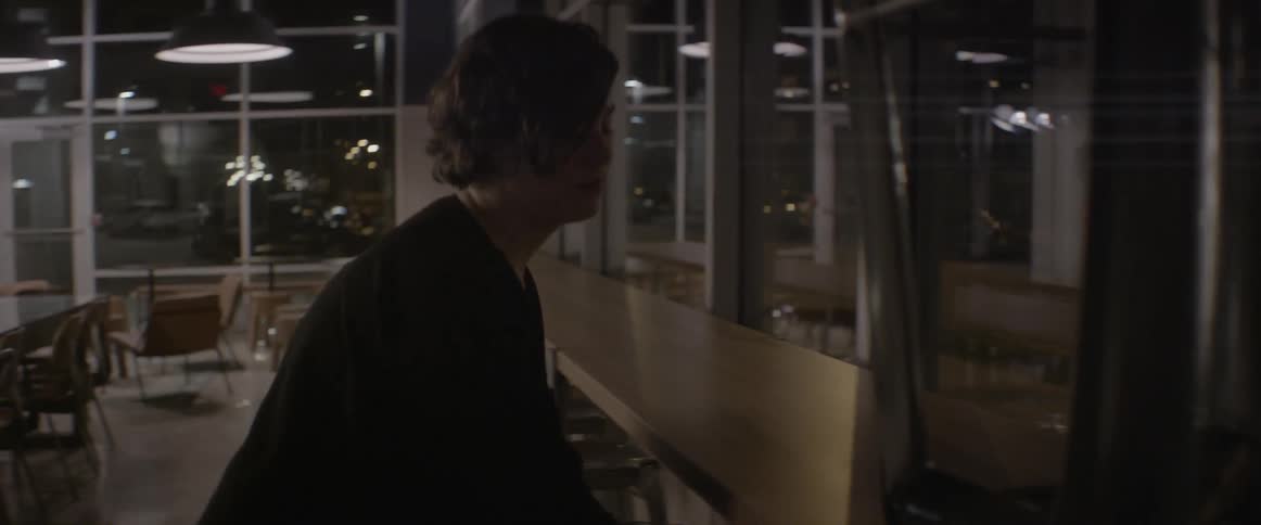 A woman takes stools off a countertop in a cafe at night