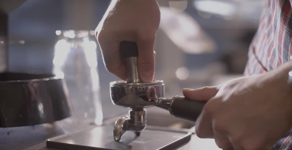 Barista pushes top of grinder down