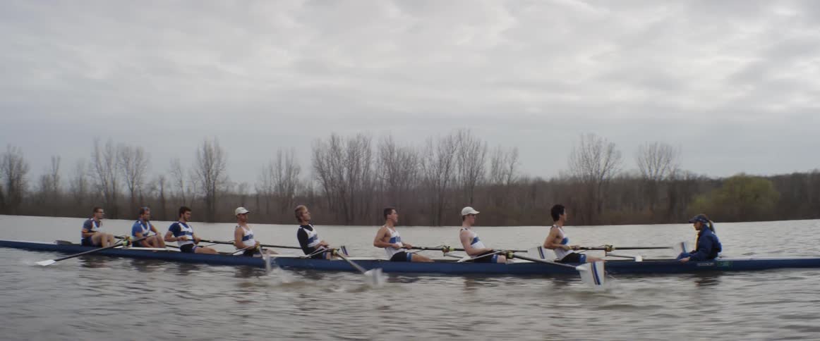 Men in a team are sculling down a river
