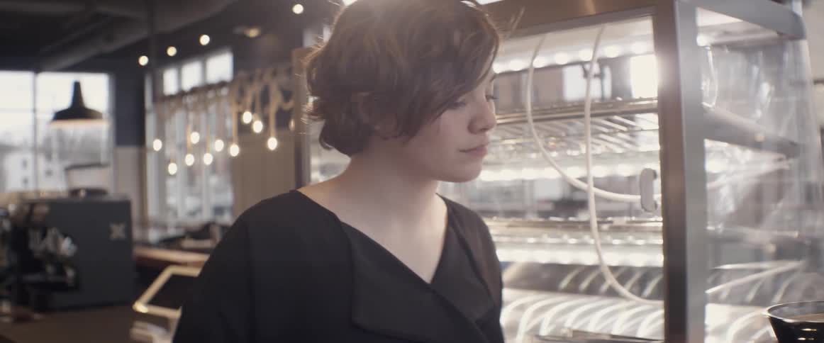A female barista watches as coffee steams