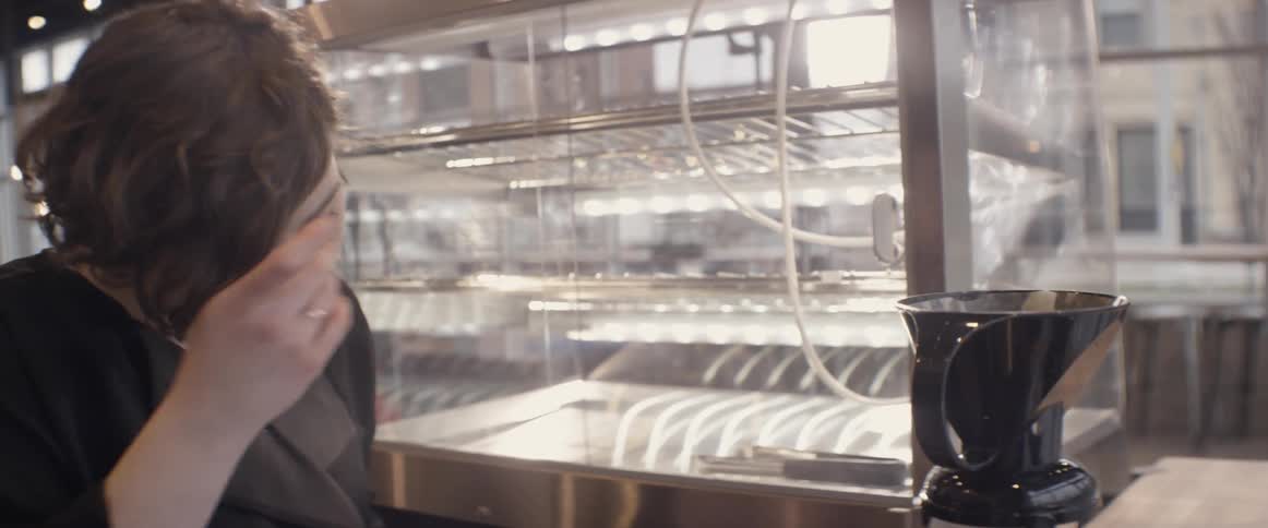 A female barista pours coffee into a glass