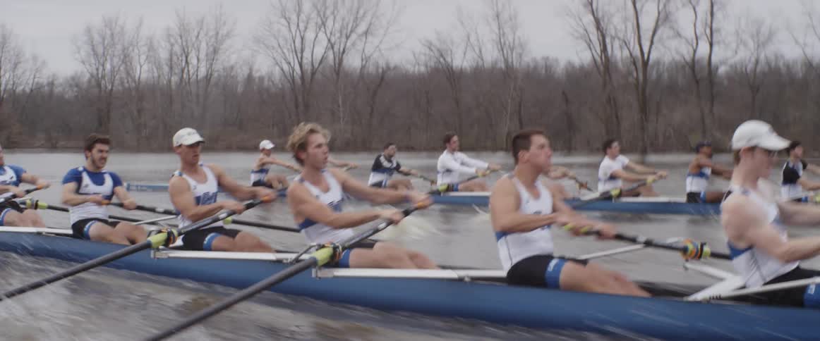 Male rowing teams compete on an overcast day
