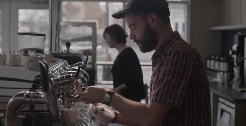 A man prepares a coffee drink in a coffeehouse
