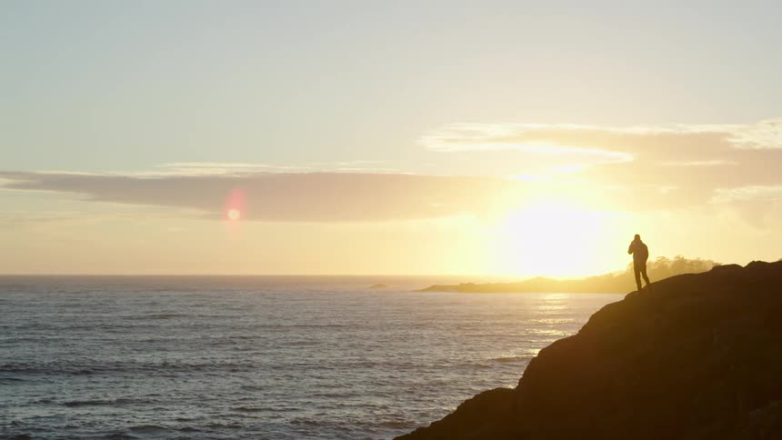 A man is standing on rocks by the shore