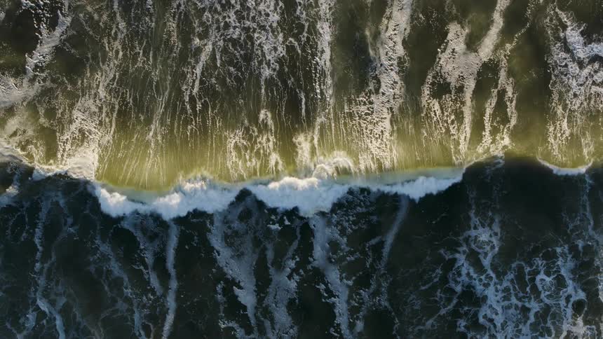 Aerial of ocean waves breaking against the shore