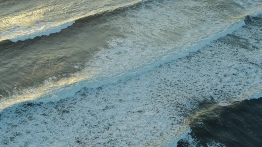 Aerial of ocean waves breaking against the beach