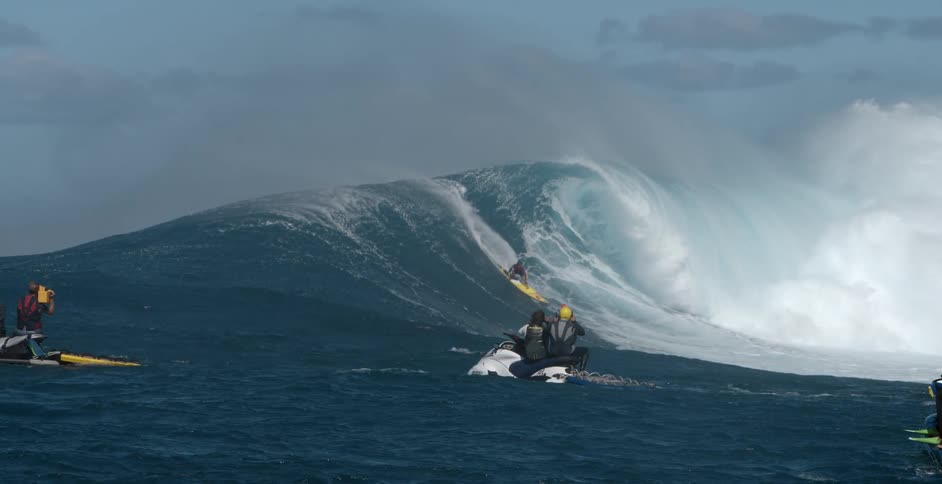 People on jet ski looking at a surfer ride a wave in the ocean