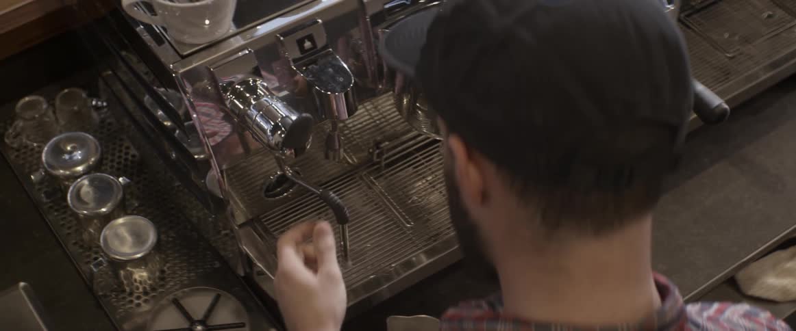 Barista pouring a glass and then cleaning his machine