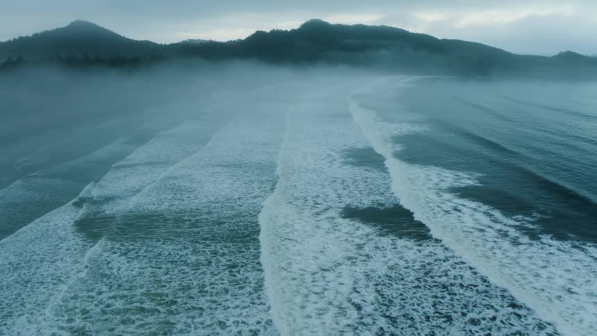 Aerial view of ocean waves breaking against the beach