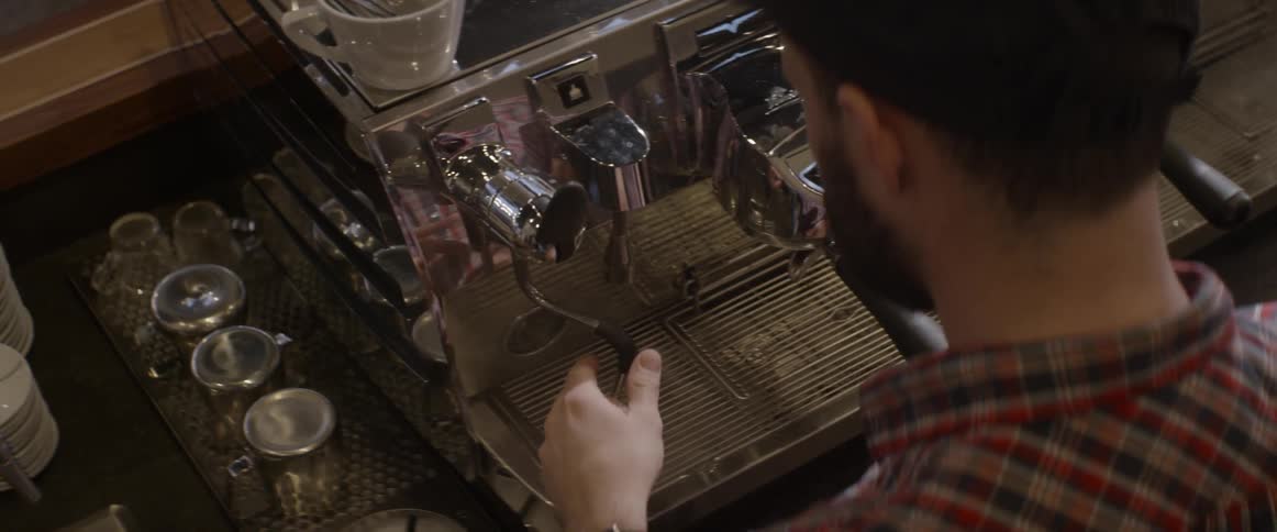 A man is operating a coffee machine in a shop
