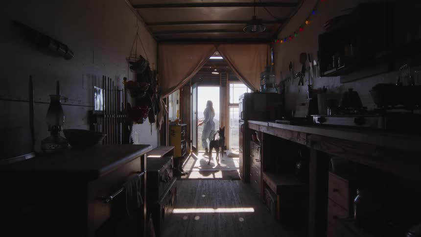 A woman walks out of her home with her dog