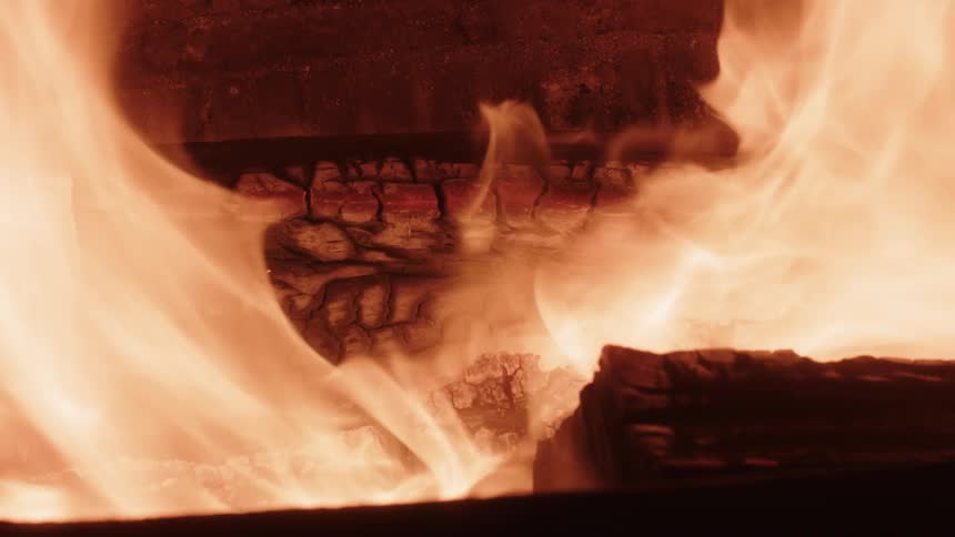 Flames waver as charred fireplace logs burn