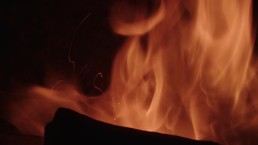 Flames waver as a fireplace log burns in the darkness