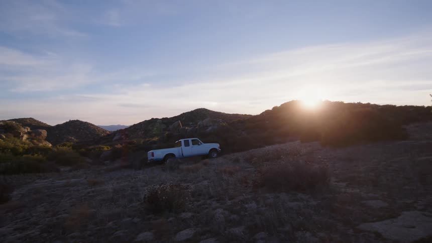 A truck drives uphill at sunrise
