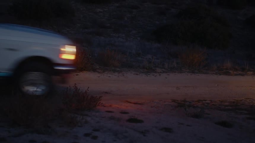 A white pickup truck drives down country road in the evening