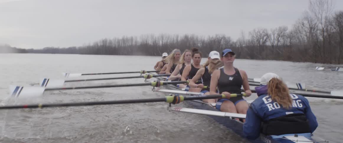 A female rowing team rows on an overcast day