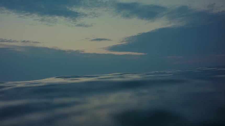 Light shines on the water as it ripples and waves under a cloudy sky