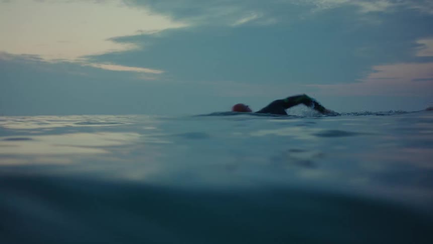 Man diving and swimming in the open sea under a morning sky