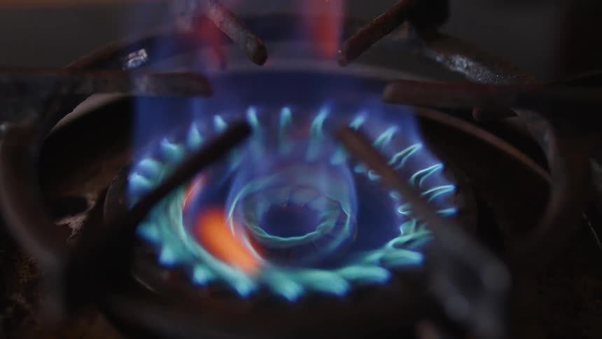 A blue flame rises from the gas burner to reach over the top of the grate