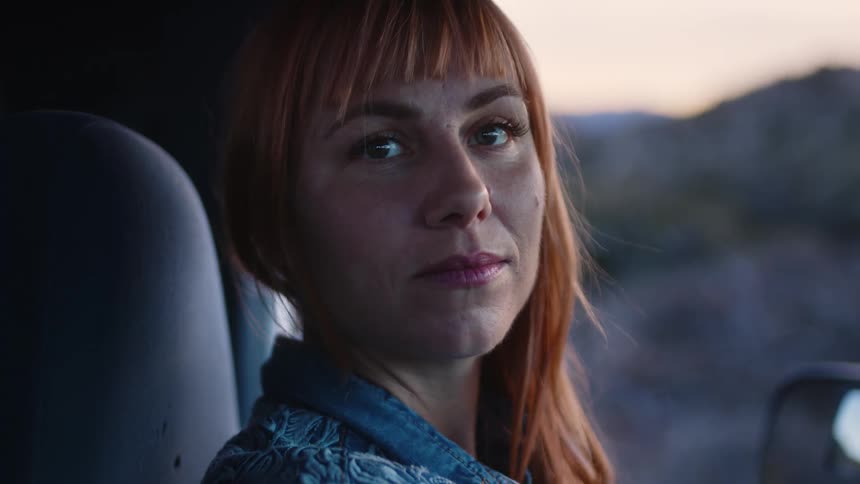Close up of the face of a woman sitting on a car in the countryside
