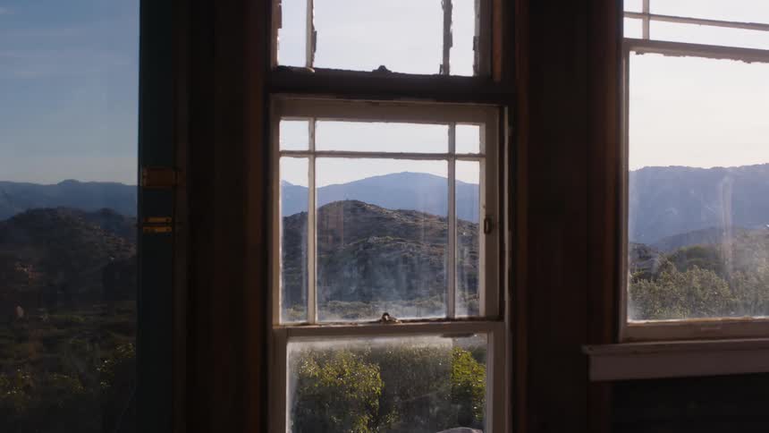 A glass window overlooking the landscape of hills and trees