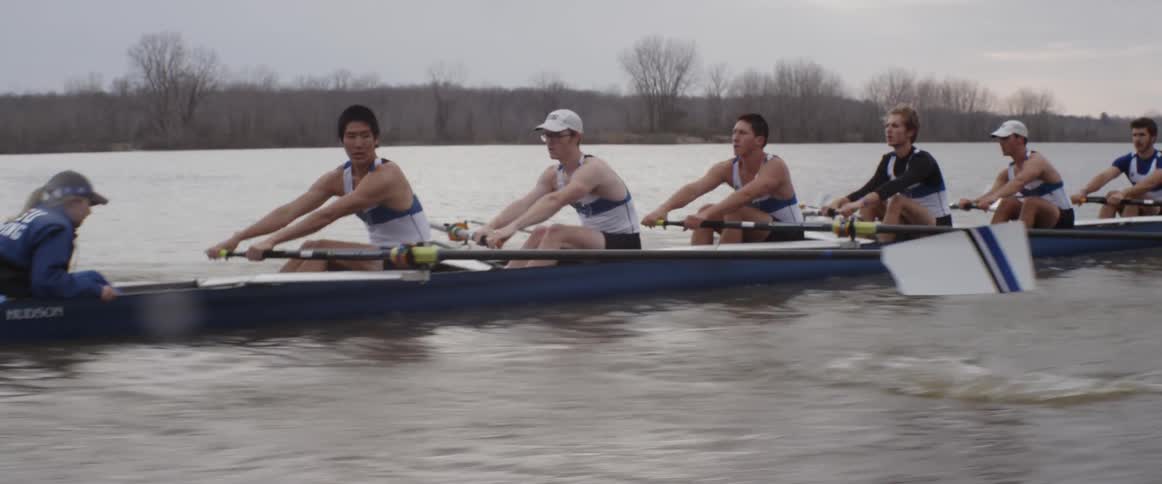 A line of people in a rowboat race in the water
